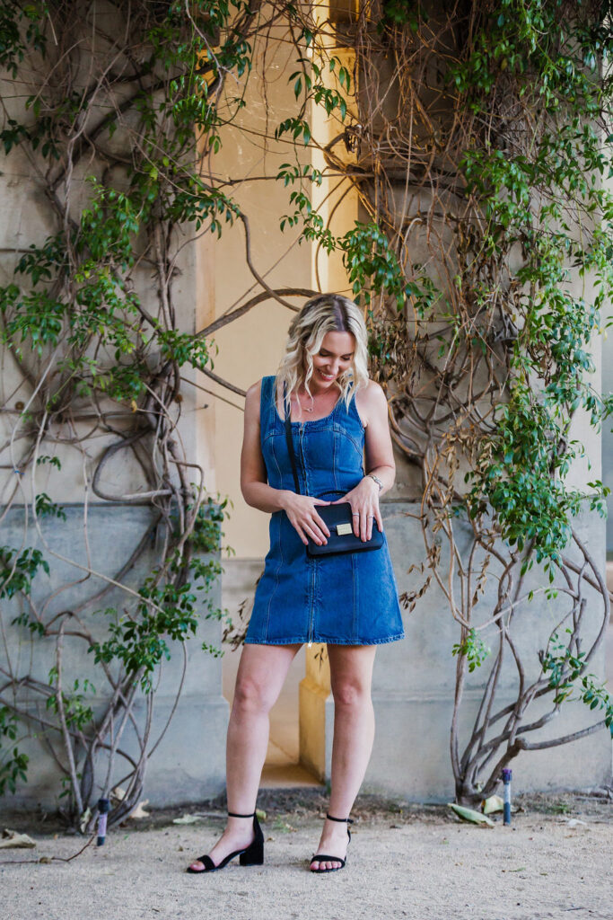 Fashion stylist Jaquelyn Wahidi wears a denim dress with black handbag and heels.