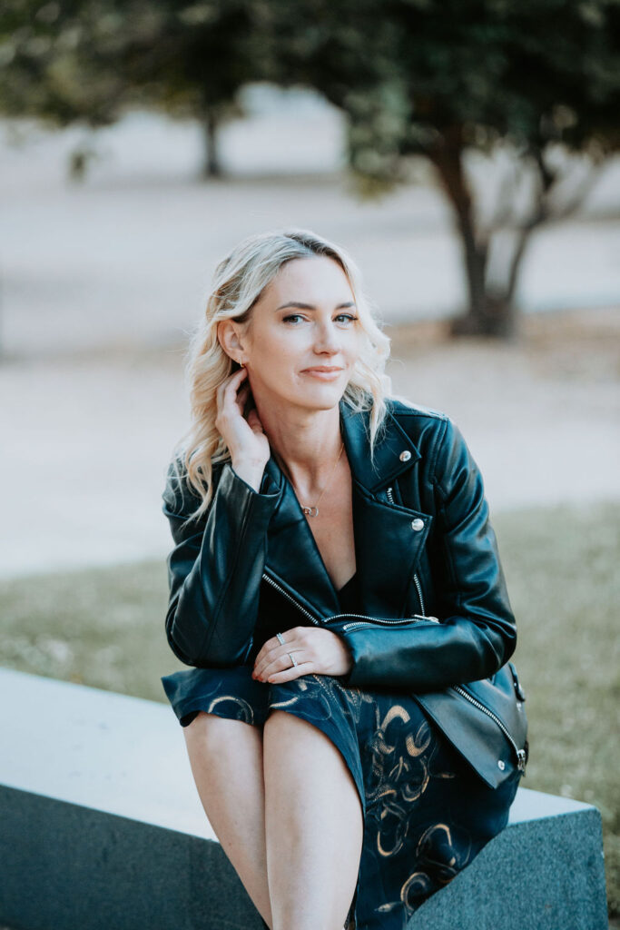 Personal stylist Jaquelyn Wahidi sits in front of a civic building in a black leather jacket and slip dress.